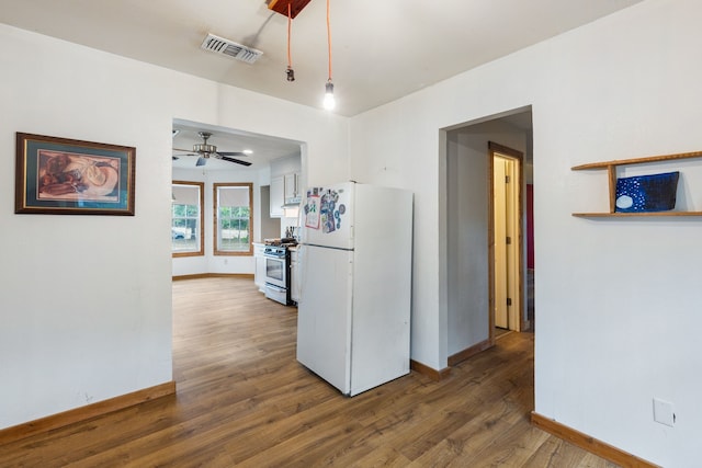 kitchen with gas stove, dark hardwood / wood-style floors, ceiling fan, and white fridge