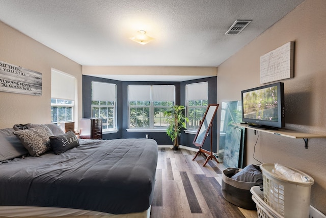 bedroom featuring multiple windows, hardwood / wood-style floors, and a textured ceiling