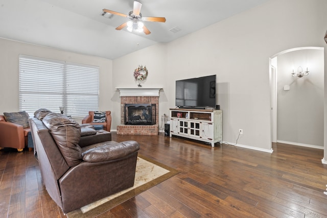 living room featuring a fireplace, vaulted ceiling, dark wood-type flooring, and ceiling fan