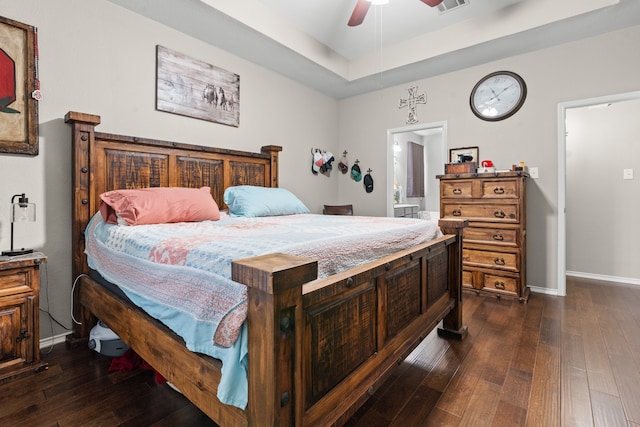 bedroom with a tray ceiling, dark hardwood / wood-style floors, and ceiling fan