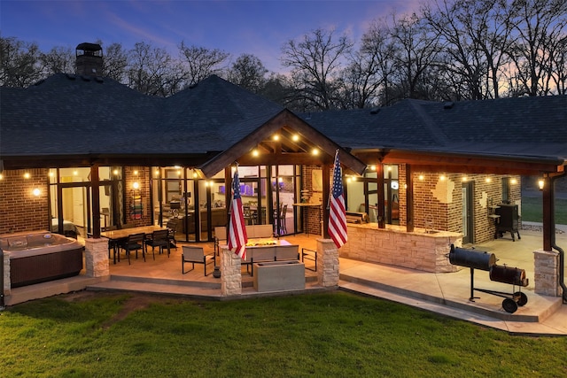 back house at dusk featuring a yard and a patio area