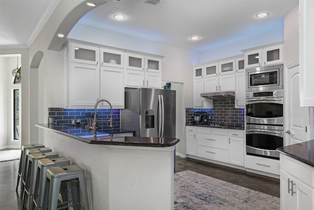 kitchen with decorative backsplash, stainless steel appliances, white cabinetry, and ornamental molding