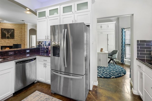 kitchen with a stone fireplace, white cabinets, and stainless steel appliances