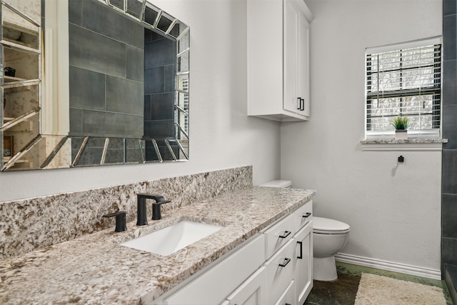 bathroom featuring a tile shower, vanity, and toilet