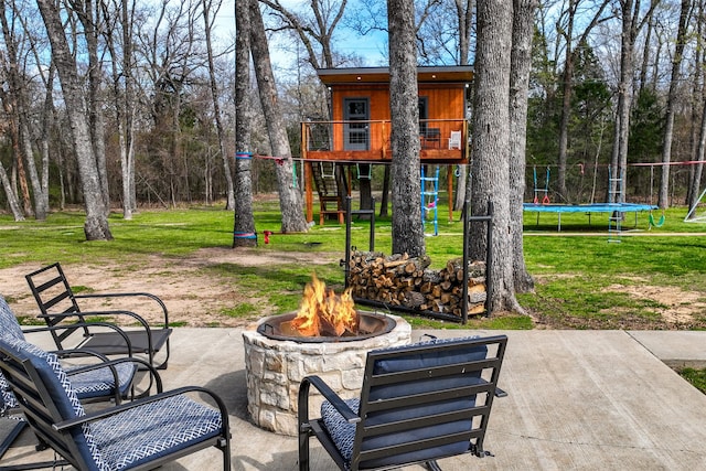 view of patio with a trampoline, a playground, and a fire pit