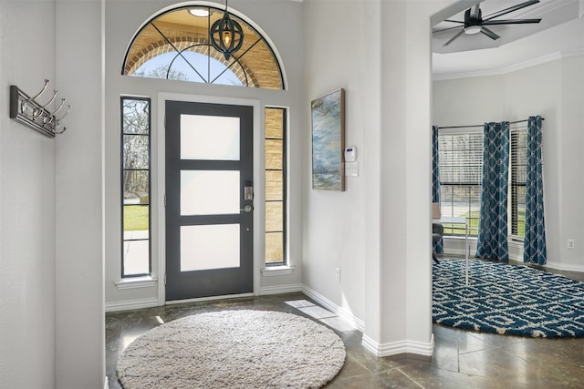 entrance foyer with ceiling fan, crown molding, and a high ceiling