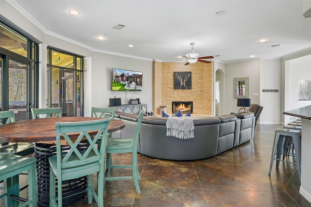 living room with a fireplace, ornamental molding, and ceiling fan