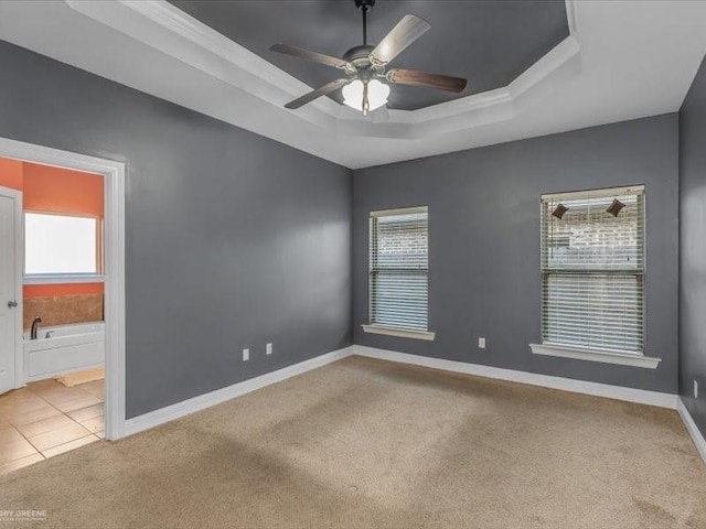 carpeted spare room featuring ceiling fan and a tray ceiling