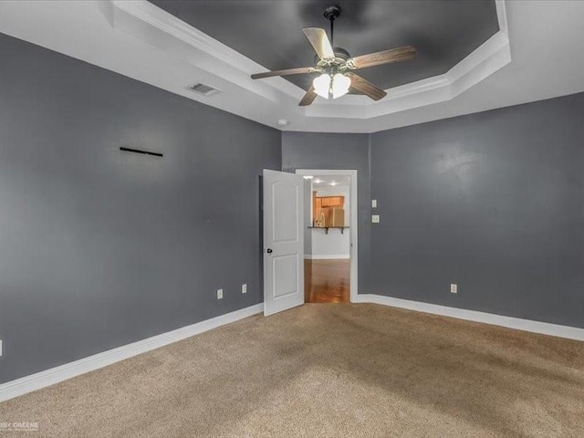 unfurnished room with ornamental molding, a raised ceiling, carpet floors, and ceiling fan