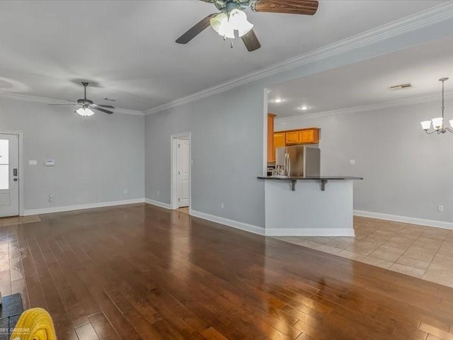 unfurnished living room featuring ceiling fan with notable chandelier, hardwood / wood-style floors, and ornamental molding