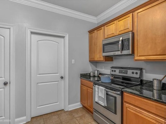 kitchen with appliances with stainless steel finishes, dark stone counters, crown molding, and light tile patterned floors