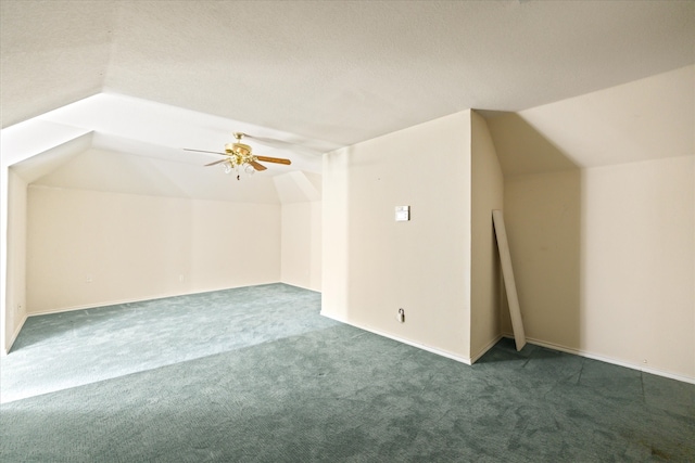 additional living space featuring ceiling fan, a textured ceiling, dark colored carpet, and vaulted ceiling