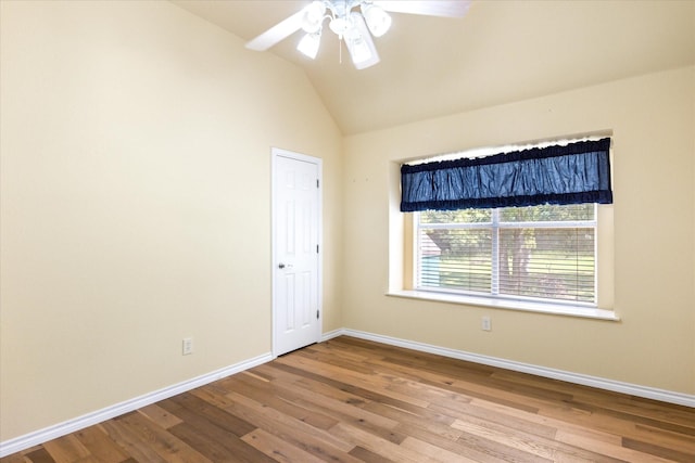 empty room with a ceiling fan, baseboards, wood finished floors, and lofted ceiling