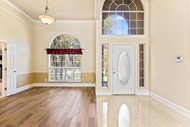 foyer featuring wood-type flooring, a high ceiling, and crown molding