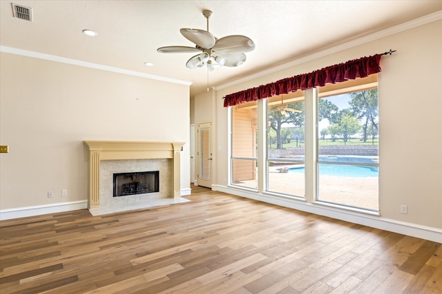 unfurnished living room with a high end fireplace, ornamental molding, ceiling fan, and hardwood / wood-style flooring