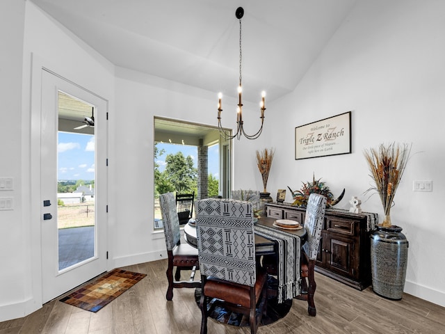 dining space with ceiling fan with notable chandelier, wood-type flooring, and lofted ceiling