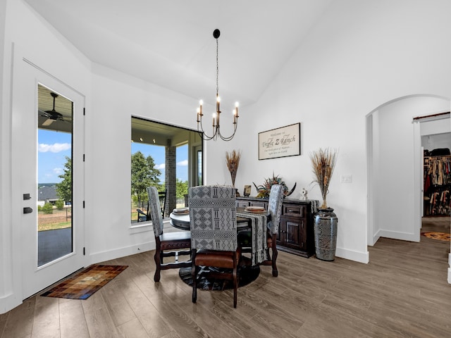 dining room featuring ceiling fan with notable chandelier, plenty of natural light, hardwood / wood-style floors, and high vaulted ceiling