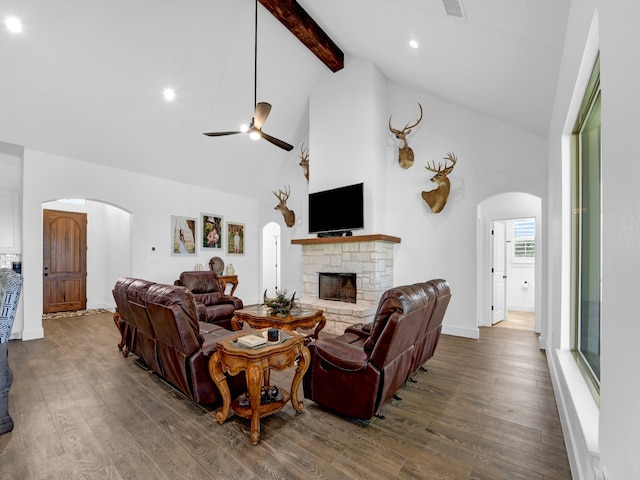 living room featuring dark hardwood / wood-style flooring, ceiling fan, high vaulted ceiling, and a stone fireplace