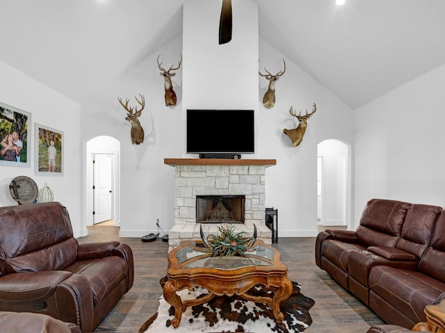 living room featuring a stone fireplace, dark hardwood / wood-style flooring, and high vaulted ceiling