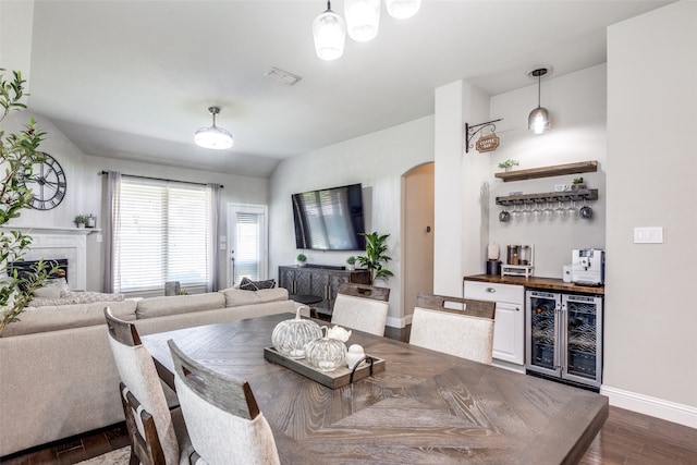 dining area with indoor bar, wine cooler, a tile fireplace, and dark hardwood / wood-style flooring