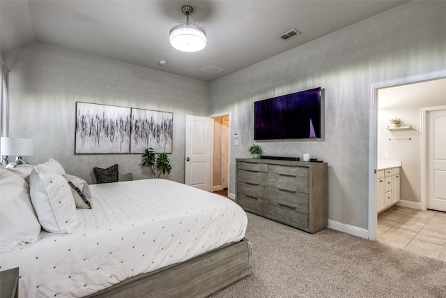 bedroom with light carpet, lofted ceiling, and ensuite bath