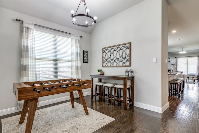 rec room featuring vaulted ceiling, a notable chandelier, and dark hardwood / wood-style flooring