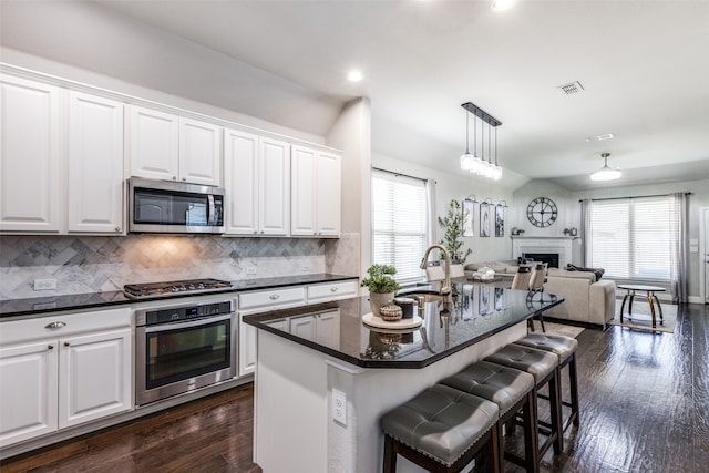 kitchen with white cabinets, a kitchen island with sink, stainless steel appliances, and a healthy amount of sunlight