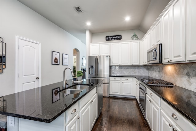 kitchen with appliances with stainless steel finishes, white cabinetry, dark wood-type flooring, a kitchen island with sink, and sink