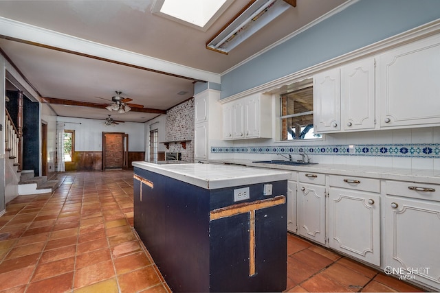 kitchen featuring a center island, sink, white cabinets, ornamental molding, and ceiling fan