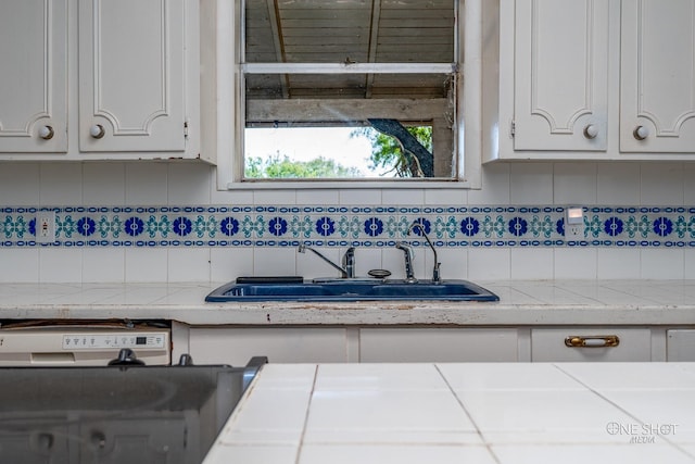 kitchen featuring sink, tasteful backsplash, and white cabinetry