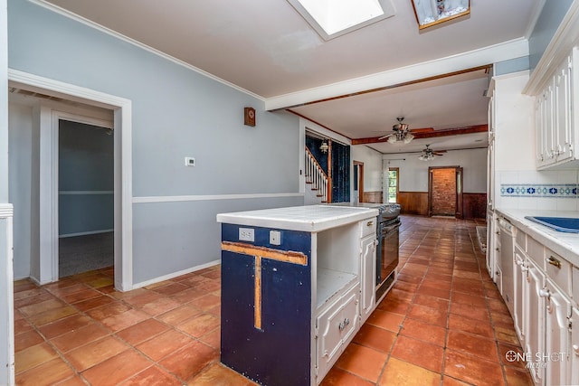 kitchen with a center island, white cabinets, backsplash, crown molding, and ceiling fan