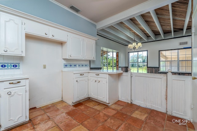 kitchen featuring white cabinets, hanging light fixtures, ornamental molding, backsplash, and an inviting chandelier