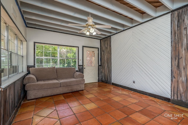 interior space with ceiling fan, wood walls, beam ceiling, and tile patterned flooring