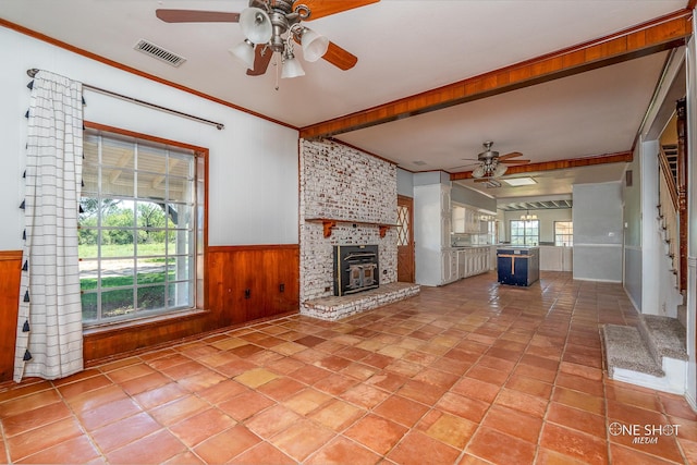 unfurnished living room featuring ornamental molding, a fireplace, wood walls, and ceiling fan