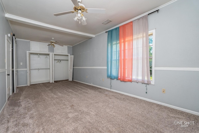 unfurnished bedroom with ceiling fan, crown molding, a barn door, and carpet