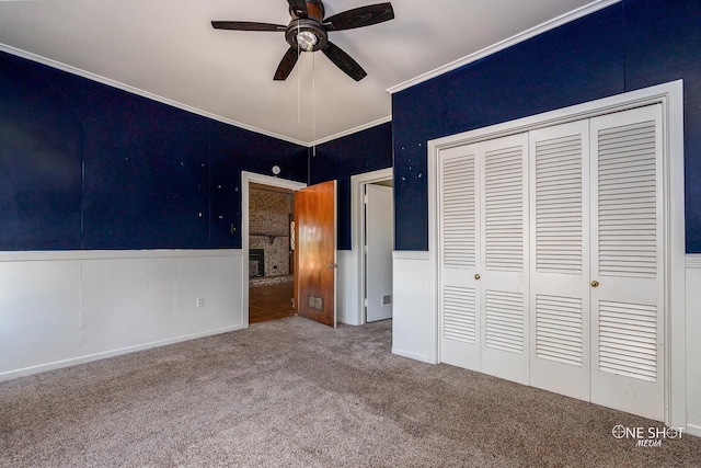 unfurnished bedroom with carpet floors, crown molding, ceiling fan, and a closet