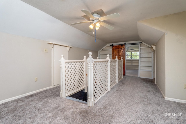 additional living space featuring carpet floors, lofted ceiling, ceiling fan, and a barn door