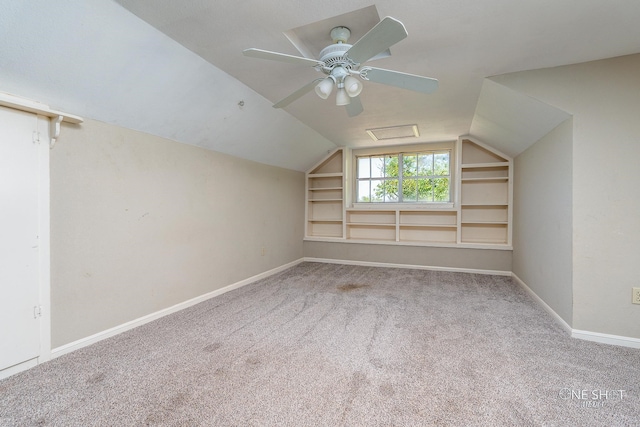 bonus room featuring built in shelves, carpet, ceiling fan, and vaulted ceiling