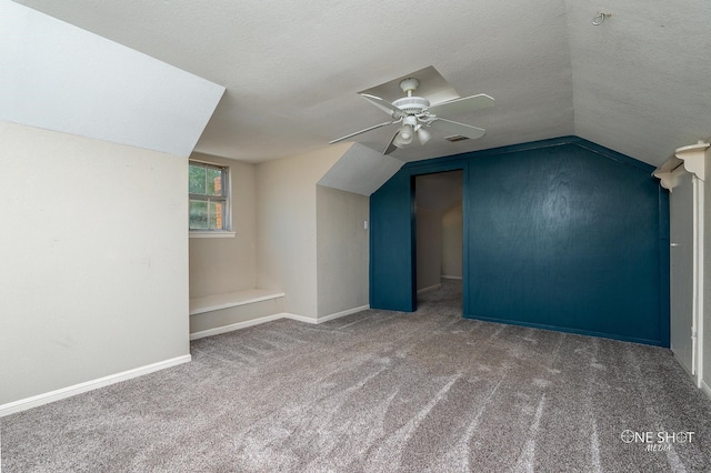 bonus room featuring lofted ceiling, ceiling fan, carpet floors, and a textured ceiling