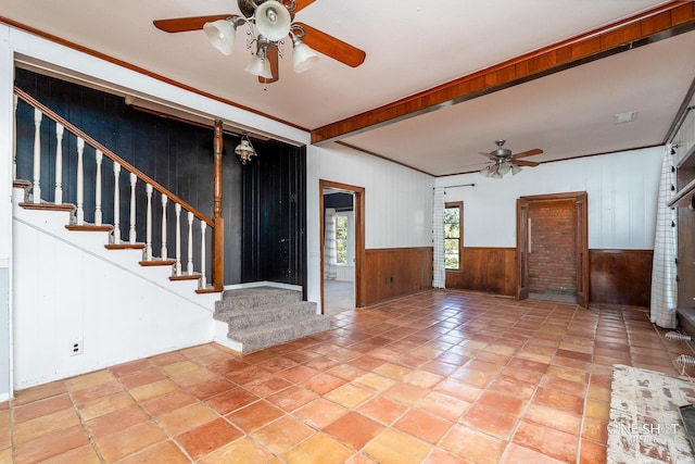 tiled entryway featuring crown molding, wood walls, and ceiling fan