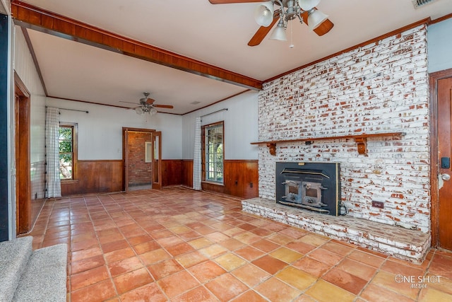 unfurnished living room with a brick fireplace, ceiling fan, and wooden walls