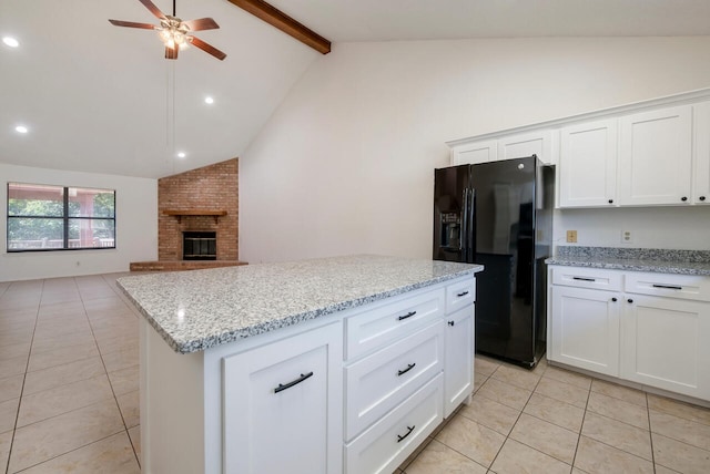 kitchen featuring ceiling fan, black fridge, white cabinets, lofted ceiling with beams, and a fireplace