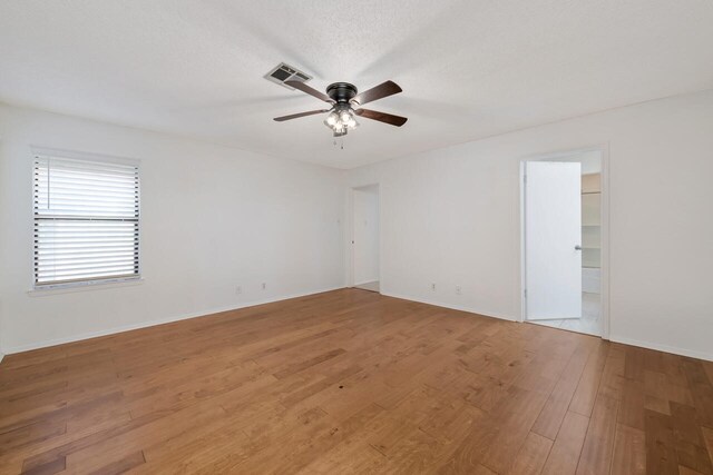 unfurnished room with ceiling fan, hardwood / wood-style floors, and a textured ceiling