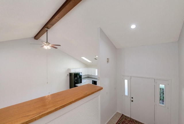entryway featuring beamed ceiling, ceiling fan, a skylight, and high vaulted ceiling