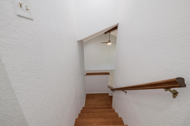 stairway with vaulted ceiling, ceiling fan, and hardwood / wood-style floors