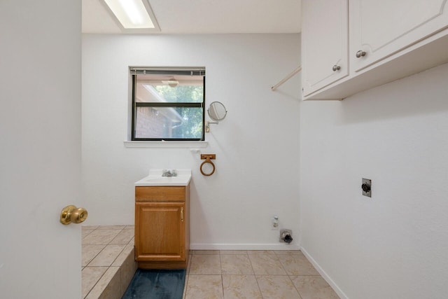 clothes washing area with light tile patterned floors, sink, electric dryer hookup, and cabinets