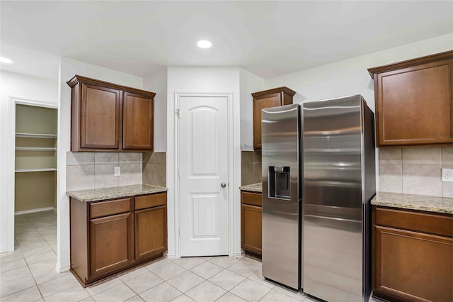 kitchen featuring backsplash, light tile patterned floors, and stainless steel fridge with ice dispenser