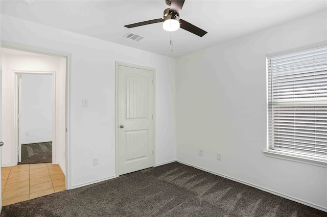 unfurnished bedroom with dark colored carpet, ceiling fan, and a closet