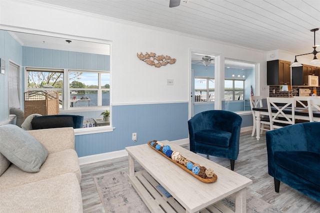 living room featuring crown molding, light wood-style floors, and a ceiling fan