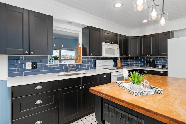 kitchen featuring decorative backsplash, white appliances, crown molding, decorative light fixtures, and sink